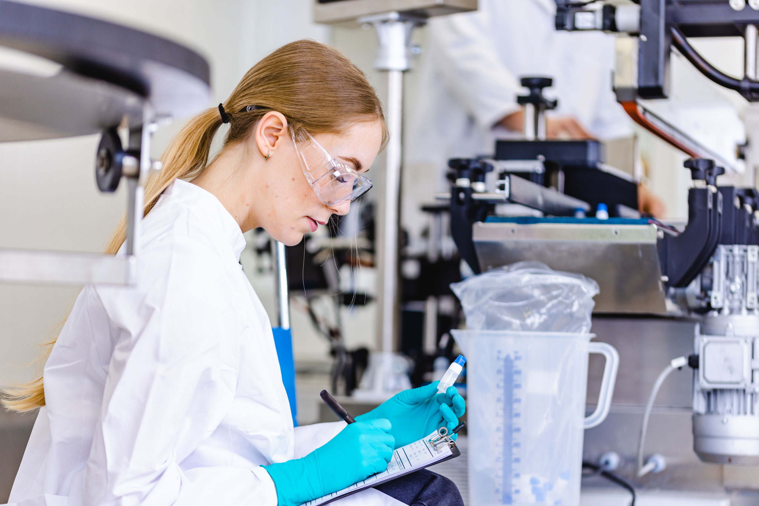 Mitarbeiterin mit Schutzbrille und Handschuhen bei der Qualitätskontrolle in der Produktion der Waldeck GmbH